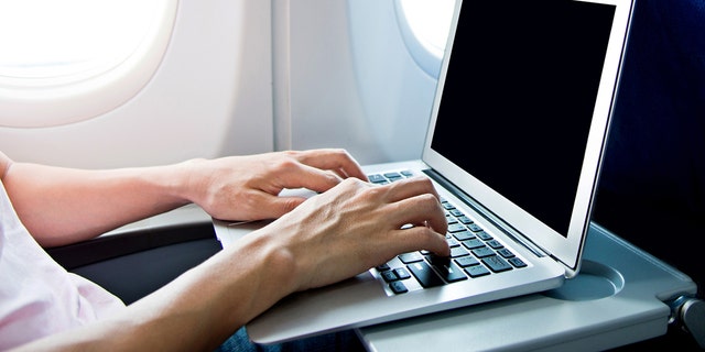 Man using laptop computer on airplane. (Boana)
