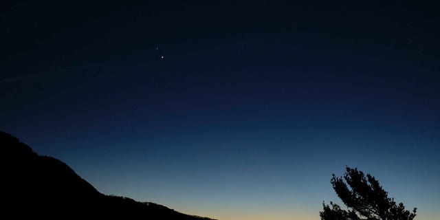 Saturn, top, and Jupiter, below, are seen after sunset from Shenandoah National Park, Sunday, Dec. 13, 2020, in Luray, Virginia. The two planets are drawing closer to each other in the sky as they head towards a "great conjunction" on December 21, where the two giant planets will appear a tenth of a degree apart. Photo Credit: (NASA/Bill Ingalls)