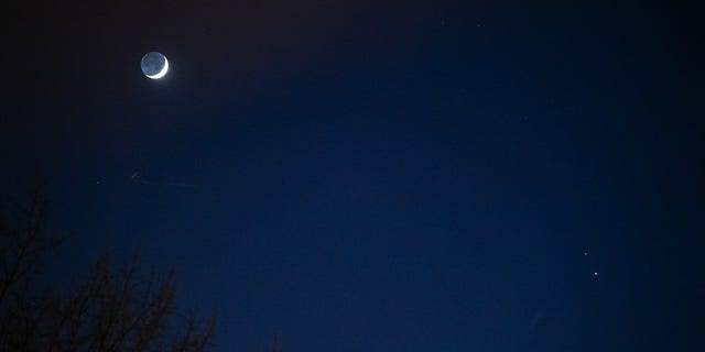 The Moon, left, Saturn, upper right, and Jupiter, lower right, are seen after sunset from Washington, DC, Thurs. Dec. 17, 2020. The two planets are drawing closer to each other in the sky as they head towards a "great conjunction" on December 21, where the two giant planets will appear a tenth of a degree apart. Photo Credit: (NASA/Aubrey Gemignani)