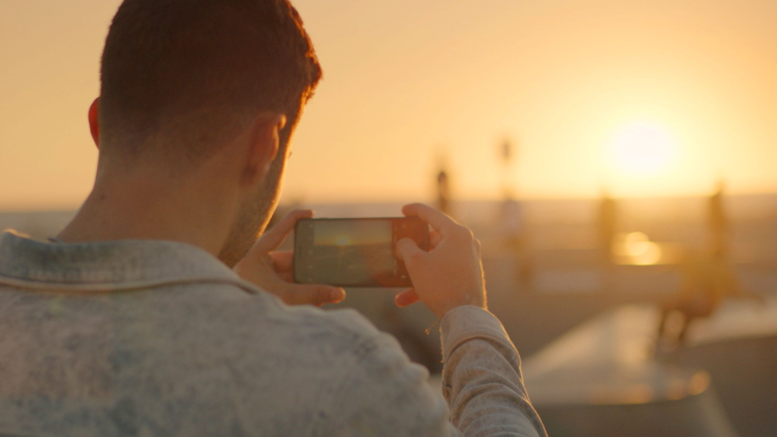 A person taking a photo of a sunset using their mobile phone