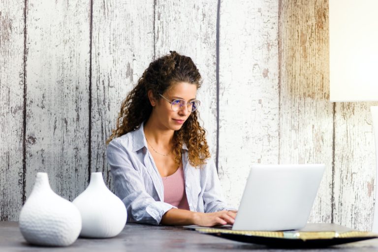 Jeune femme travaillant à distance sur un ordinateur portable depuis son domicile