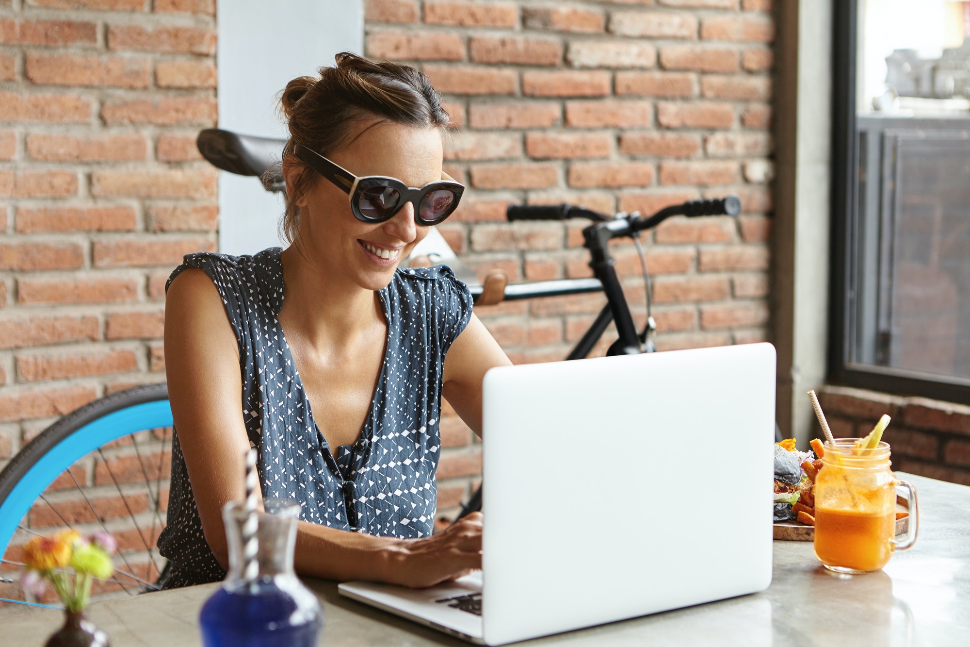 Gelukkige vrouwelijke blogger die een nieuw bericht schrijft op haar blog, met een snelle internetverbinding, zittend op