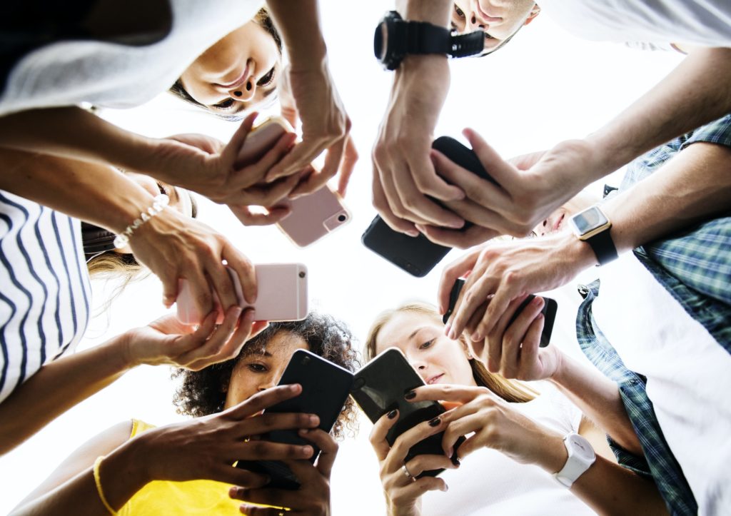 Junge Erwachsene nutzen Smartphones in einem Kreis sozialer Medien und Verbindungen