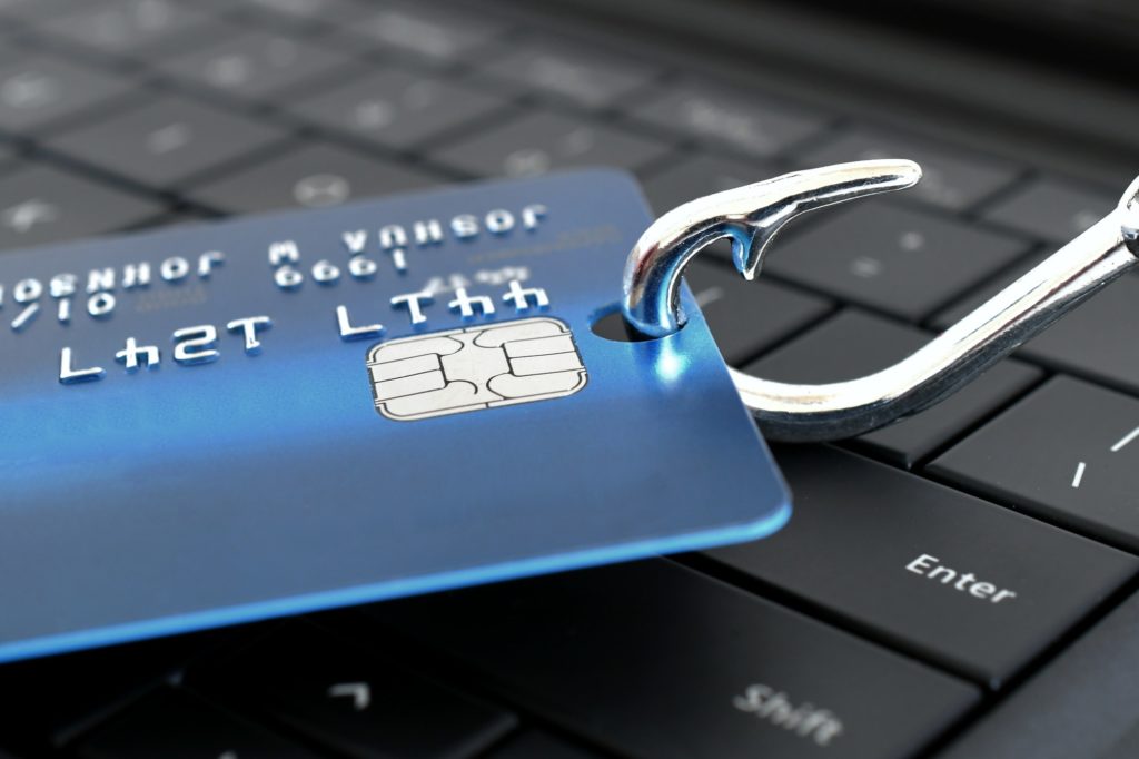 Attenzione alle e-mail di phishing scam - Concetto di carta di credito su un amo da pesca sulla tastiera del computer