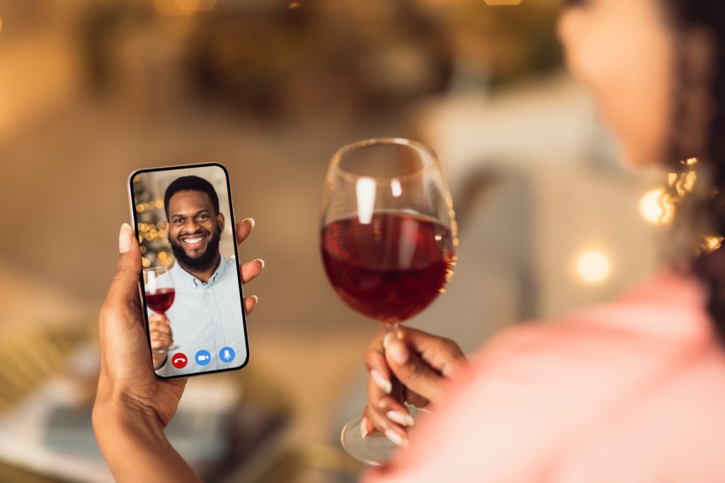Black couple having online date, drinking red wine