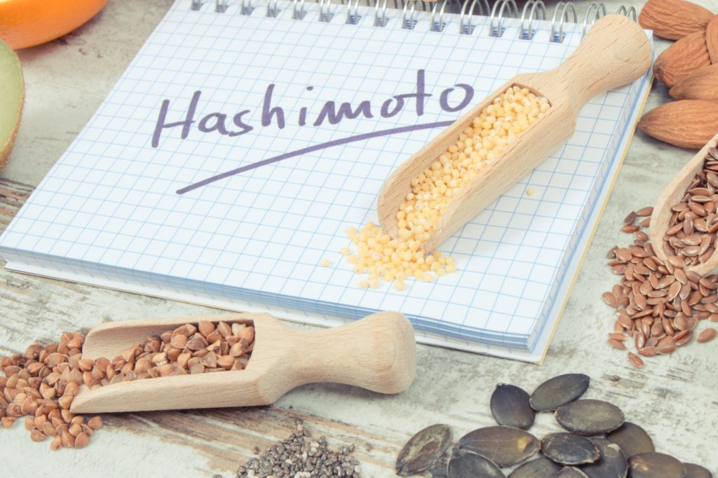 Anteckningsblock med inskription hashimoto och de bästa ingredienserna eller produkterna för en frisk sköldkörtel