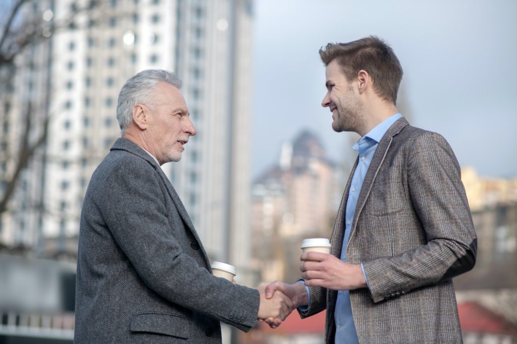 Молодой бизнесмен и его зрелый наставник пожимают друг другу руки