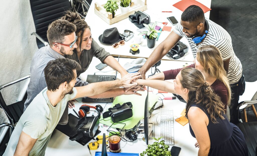 Groupe de jeunes employés d'une startup empilant les mains dans un studio urbain
