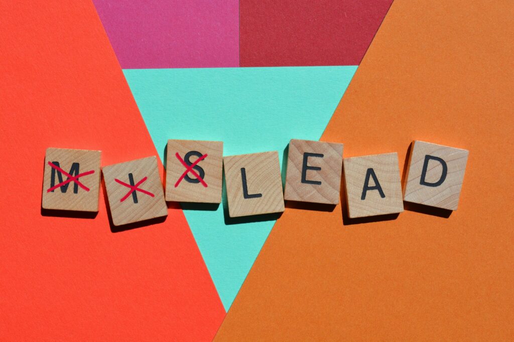 Mislead, слово из 3D букв деревянного алфавита с перечеркнутым словом mis, оставляющим слово lead.
