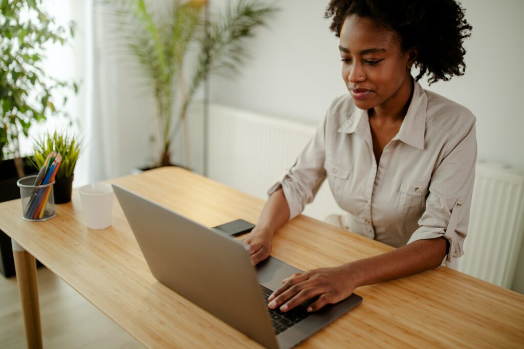 Redactor afroamericano concentrado actualizando el software en un ordenador portátil en la oficina.