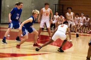 Junior Noah Millikan focuses on senior Jamir Thomas running toward the ball in a basketball game. 