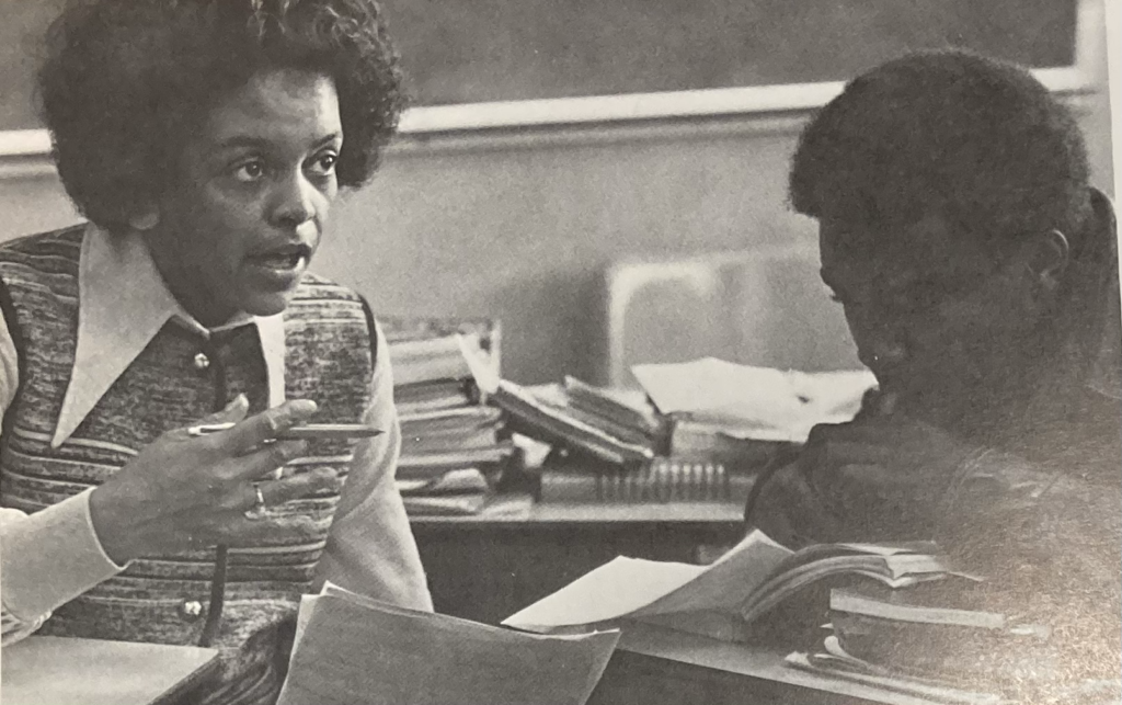 An old photo of two Black students at desks, talking