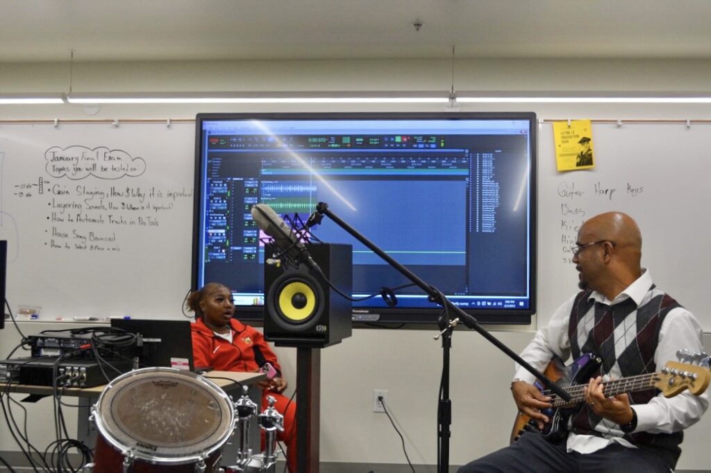 Williams demonstrates a song on electric bass for his class.