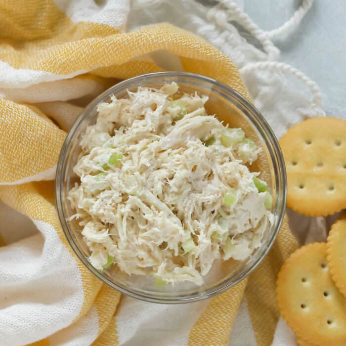 glass bowl with chicken salad on a yellow towel with butter crackers
