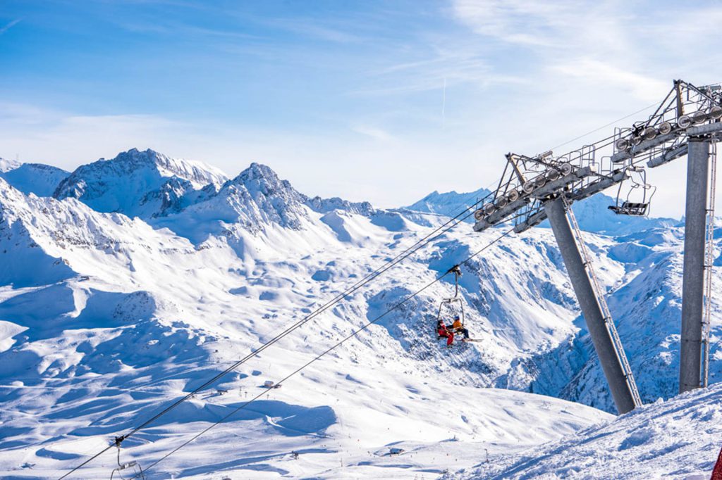 Two skiers on a chairlift ride up to the top of the ski slopes in Les Contamines