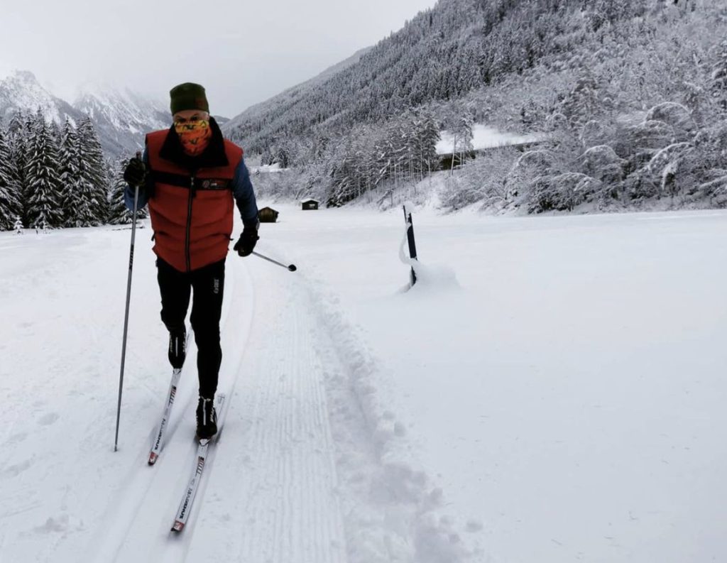 man wears covid face covering while cross-country skiing