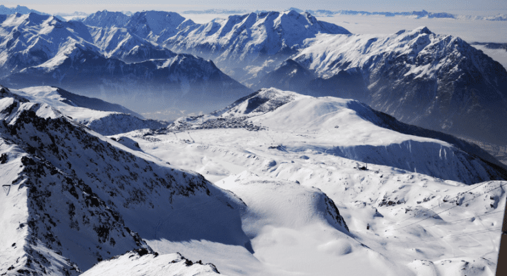 A breathtaking view of Alpe d'Huez, the iconic ski resort in the French Alps. Majestic snow-covered peaks surround the charming alpine village, where skiers and snowboarders carve down the slopes, capturing the thrill and beauty of winter sports in this renowned mountain destination.