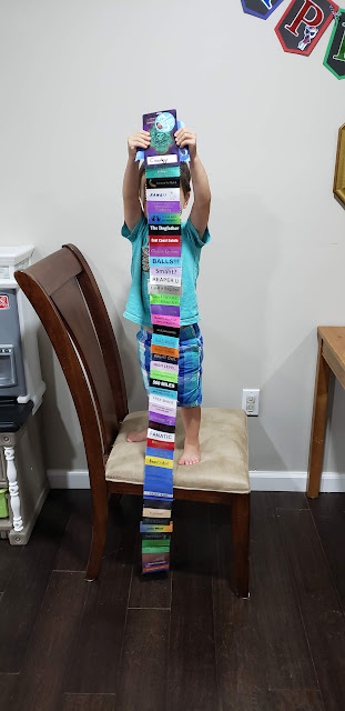 todder standing on a chair, holding con bade and train of ribbons that touch the floor