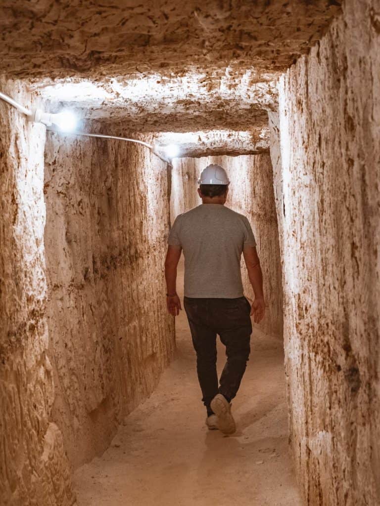 Man walking through a narrow cut passage in the opal mine in Coober Pedy, Australia