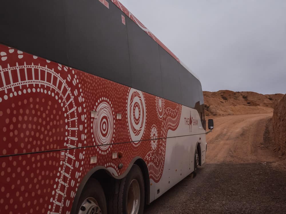 A coach with the Ghan logo park in the desert at Coober Pedy