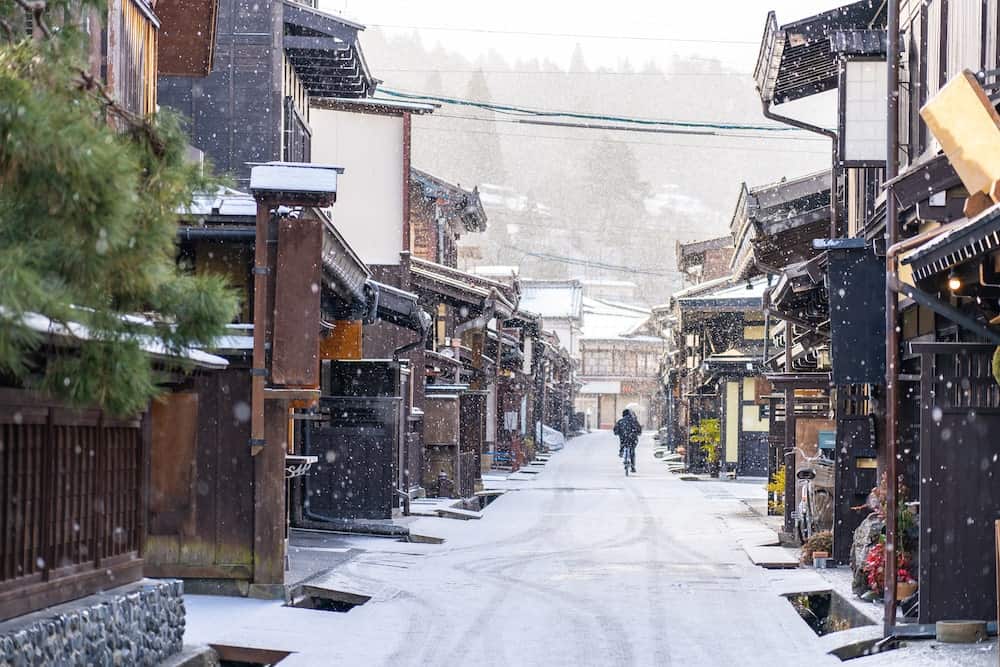 Man riding bicycle in the snow down the streets of Takayama the ancient town in Gifu Prefecture Japan