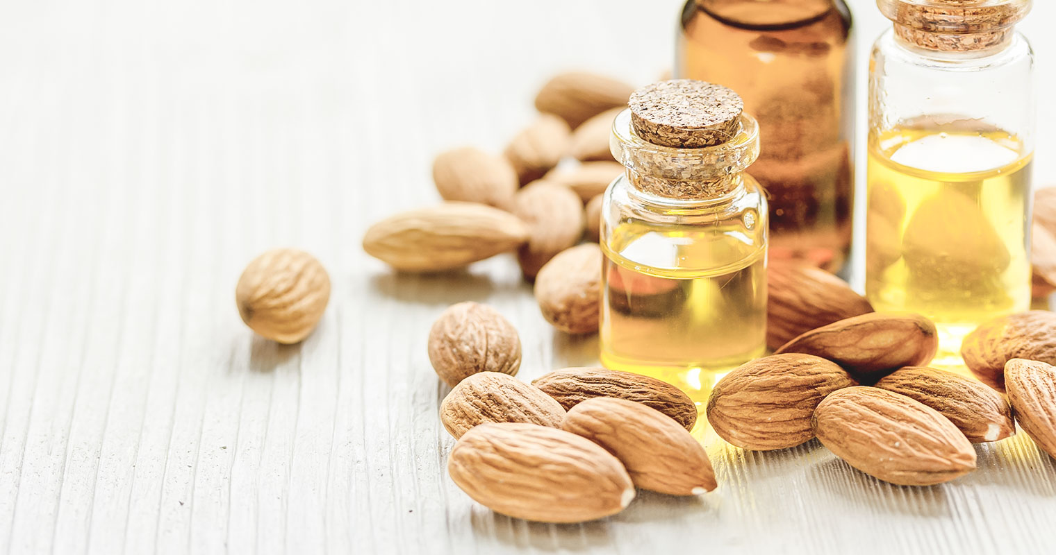 Small bottles of Almond oil surrounded by Almond seeds