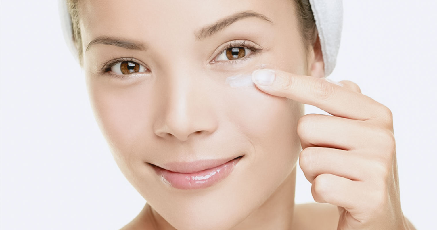 woman applying cream to her eye bags