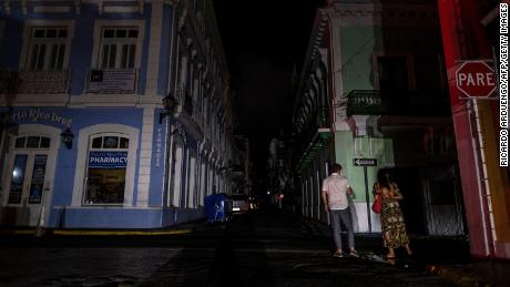 A couple walks on a dark street in San Juan after the April 6 blackout.