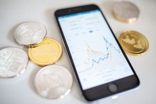  illustration of the litecoin, ripple and ethereum cryptocurrency 'altcoins' sit arranged for a photograph beside a smartphone displaying the current price chart for ethereum 