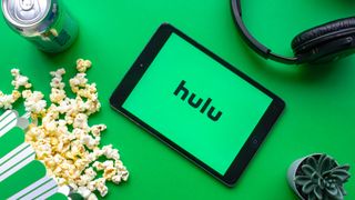 Hulu on a tablet next to food and headphones