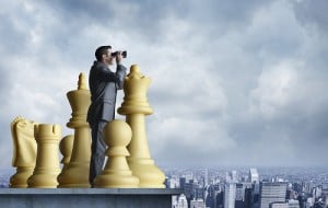 Businessman Standing Among Chess Pieces Looks Through Binoculars