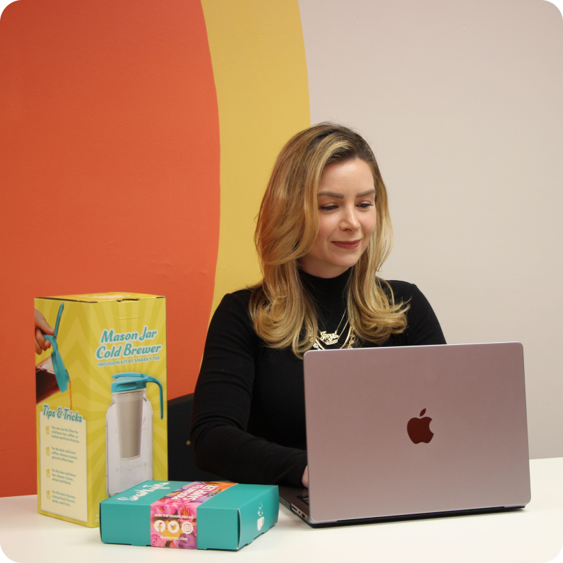 Jenni-Lyn Williams, PDG de SnarkyTea, travaillant sur son ordinateur avec les produits SnarkyTea à côté d’elle