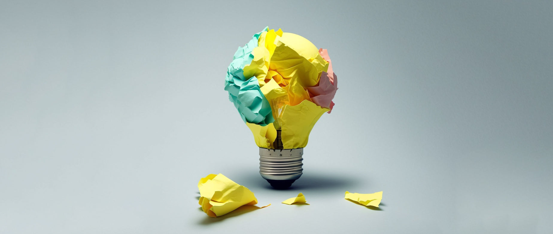 Crumpled colored paper shaped like a lightbulb on a gray background representing passive income ideas.