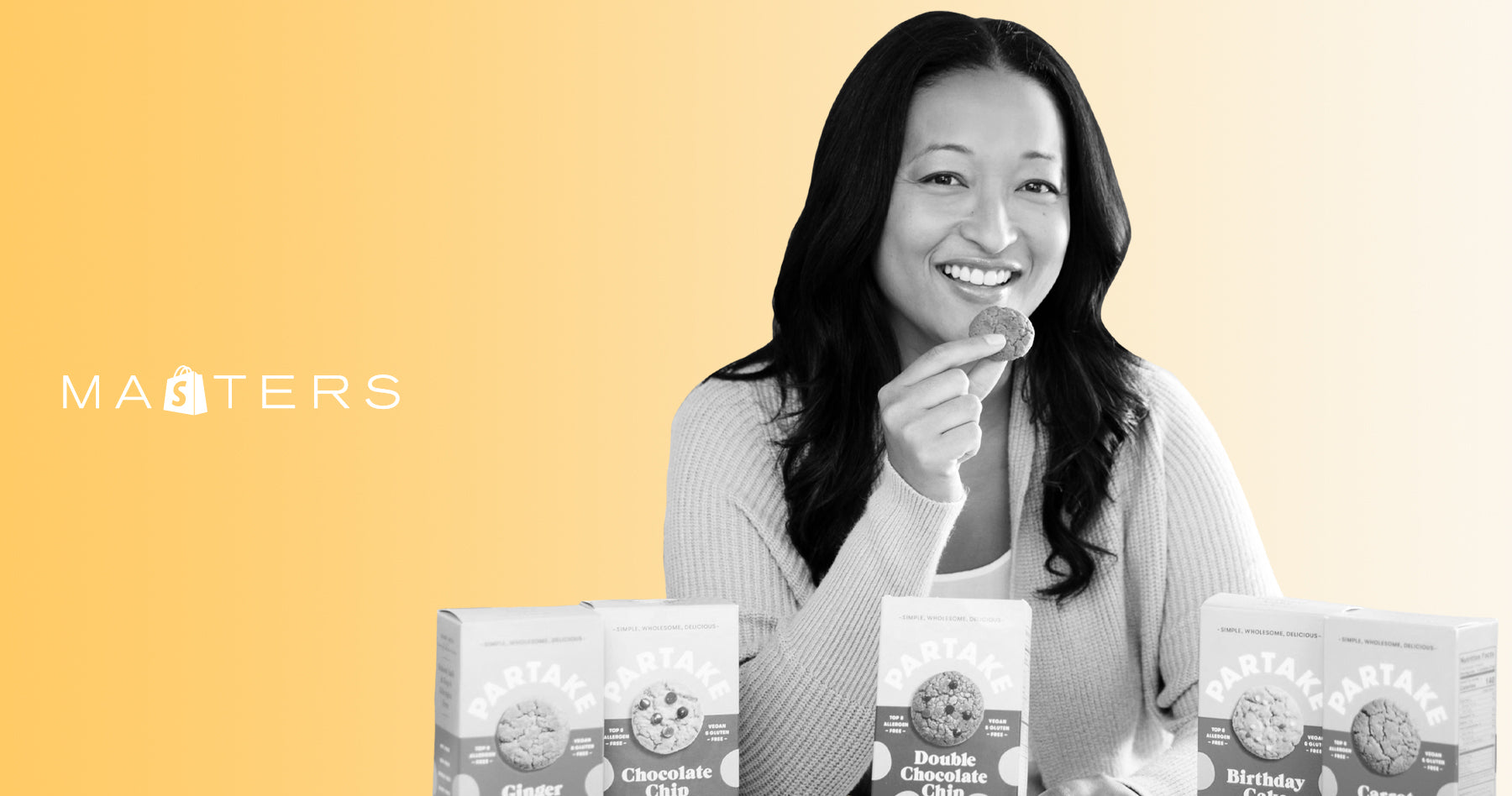  Denise Woodard in a kitchen with five different types of Partake Foods cookies displayed in front of her. 