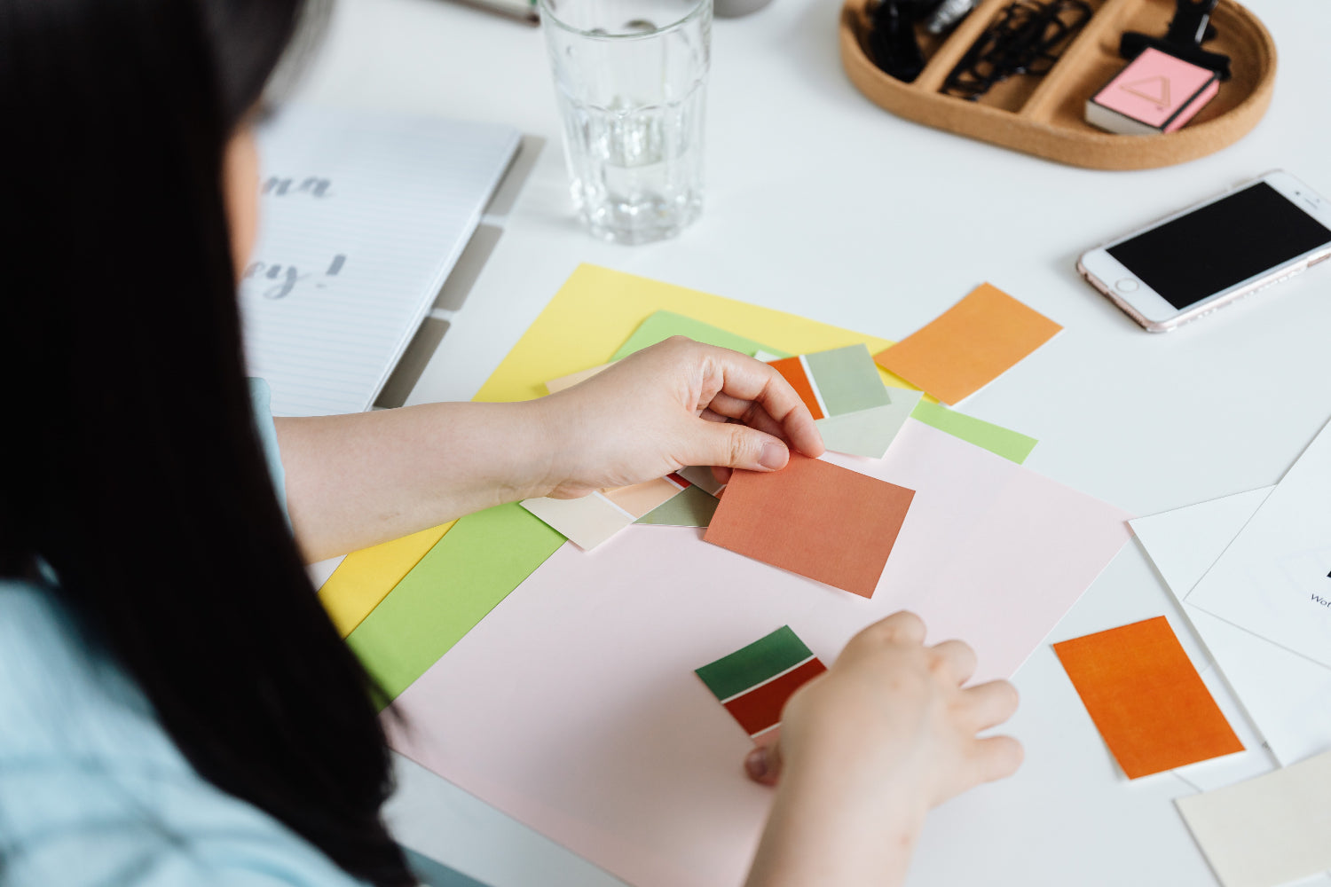 A person organizes color swatches on a table