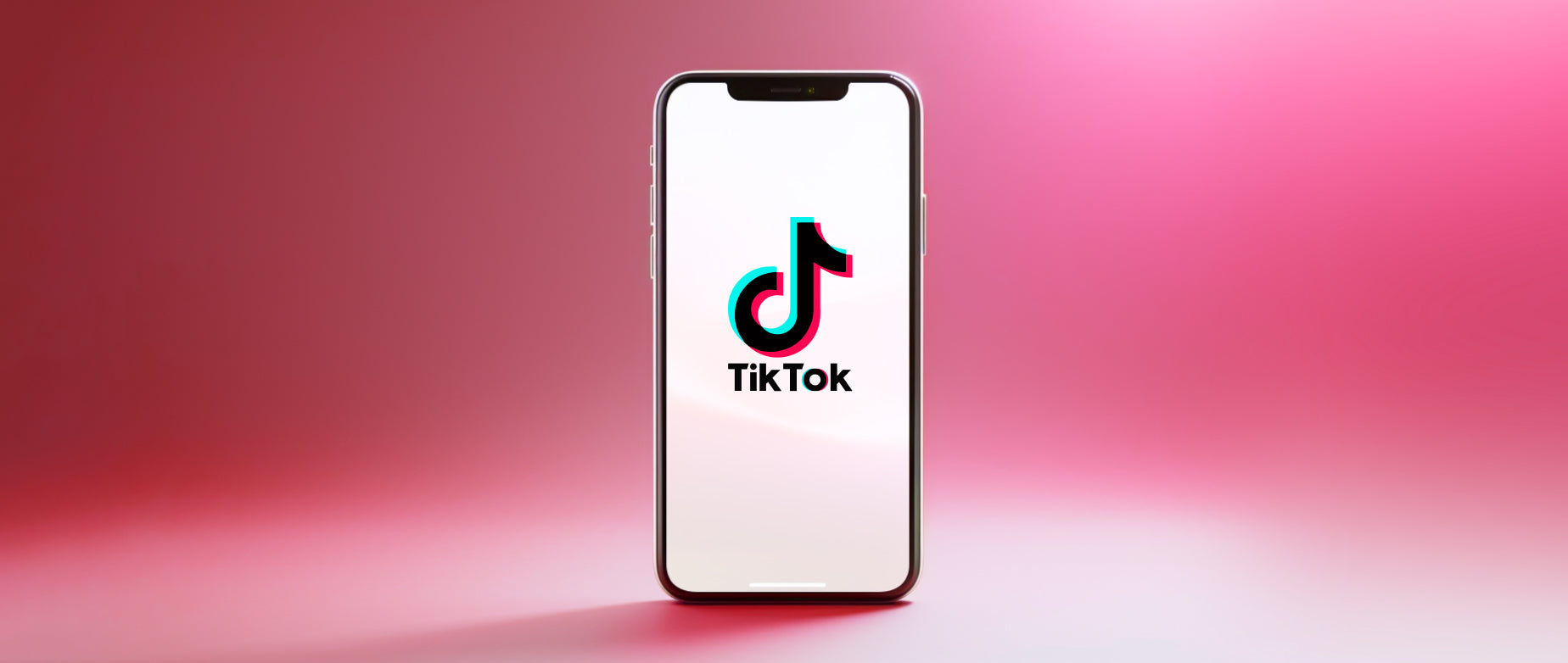 A smartphone with TikTok logo on the screen on a pink background.