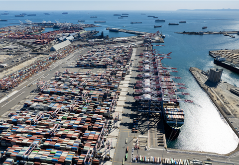 Image of the Los Angeles shipping port covered in shipping containers with more ships waiting to unload in the background.