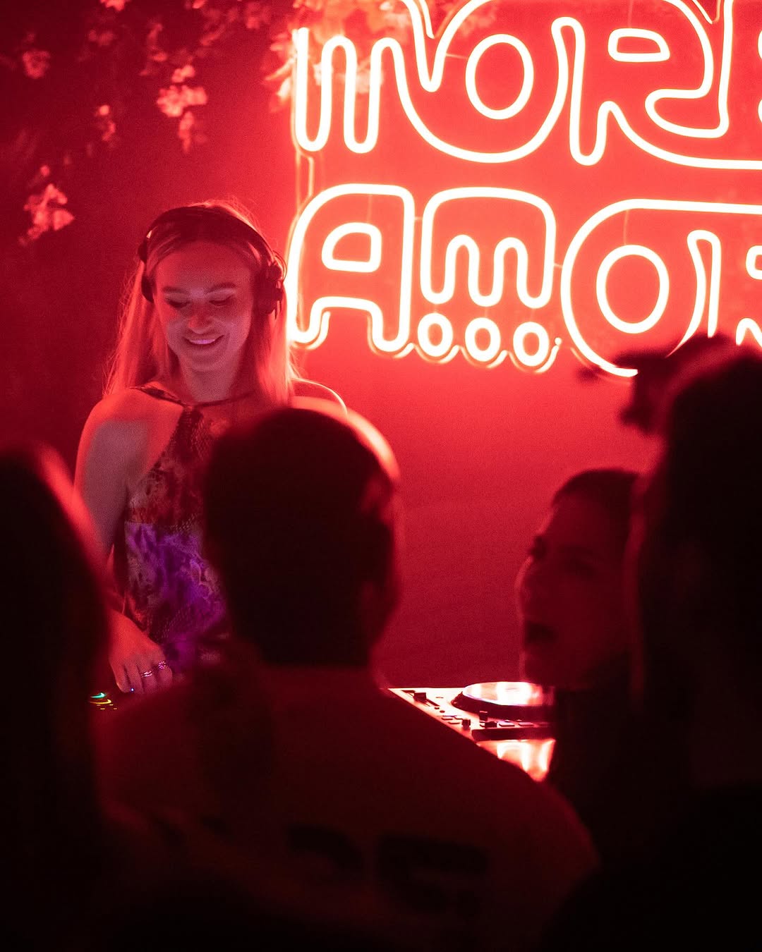 Red neon sign lighting up a DJ set at More Amore club