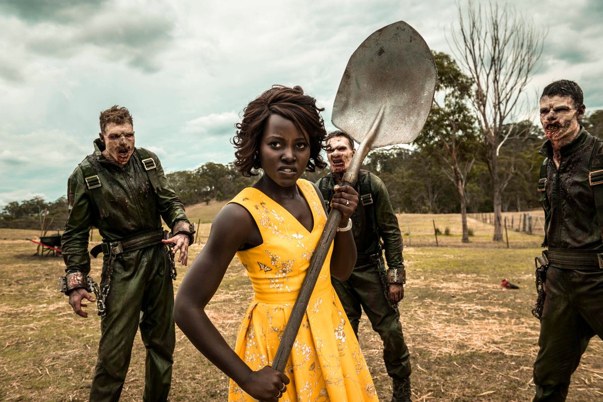 Lupita Nyong’o brandishing a shovel while surrounded by zombies in Little Monsters