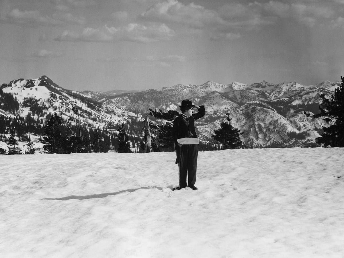 Charlie Chaplin in the Gold Rush standing in the middle of the snow atop the mountains