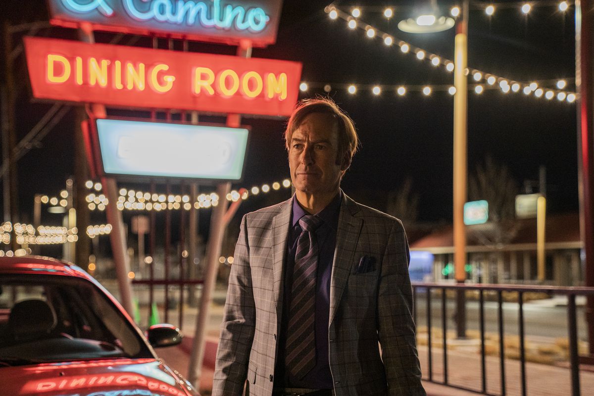 Jimmy McGill standing in front of a sign that reads “El Camino DINING ROOM” at night in Better Call Saul season 6