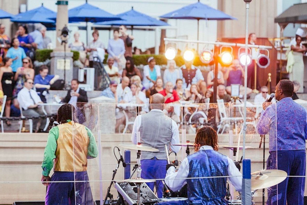 Musicians perform at an outdoor event with an audience watching.