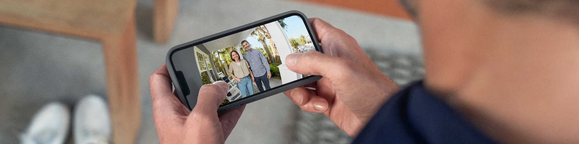 A homeowner sitting speaking to guests at the door with the Ring app.
