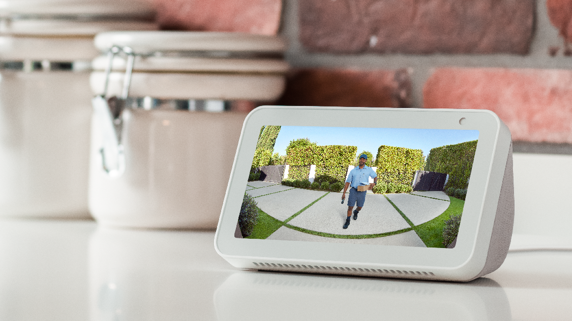 An Amazon Echo Show 5 displaying a delivery person bringing a package to a homeowner's front door.