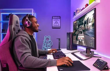 man sitting at a computer desk with a XENEON 32UHD144 Gaming Monitor