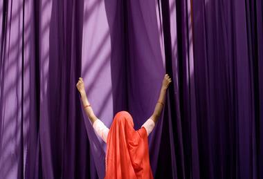 A photograph of a woman sorting drying mauve fabric