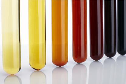 Several test tubes containing liquids that range in colour from light yellow, through orange to dark brown, representing the iodoform reaction.