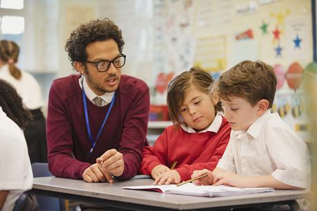 Male primary school teacher working with two young pupils