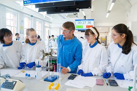 Dr Tony Raynham, UEL BSc chemistry course leader, stands in the middle of a group of four students conducting an experiment