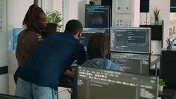 Database admins collaborating on group project compiling algorithm for new cloud computing user interface on computer. Multiethnic team of software engineers developing html script code.
